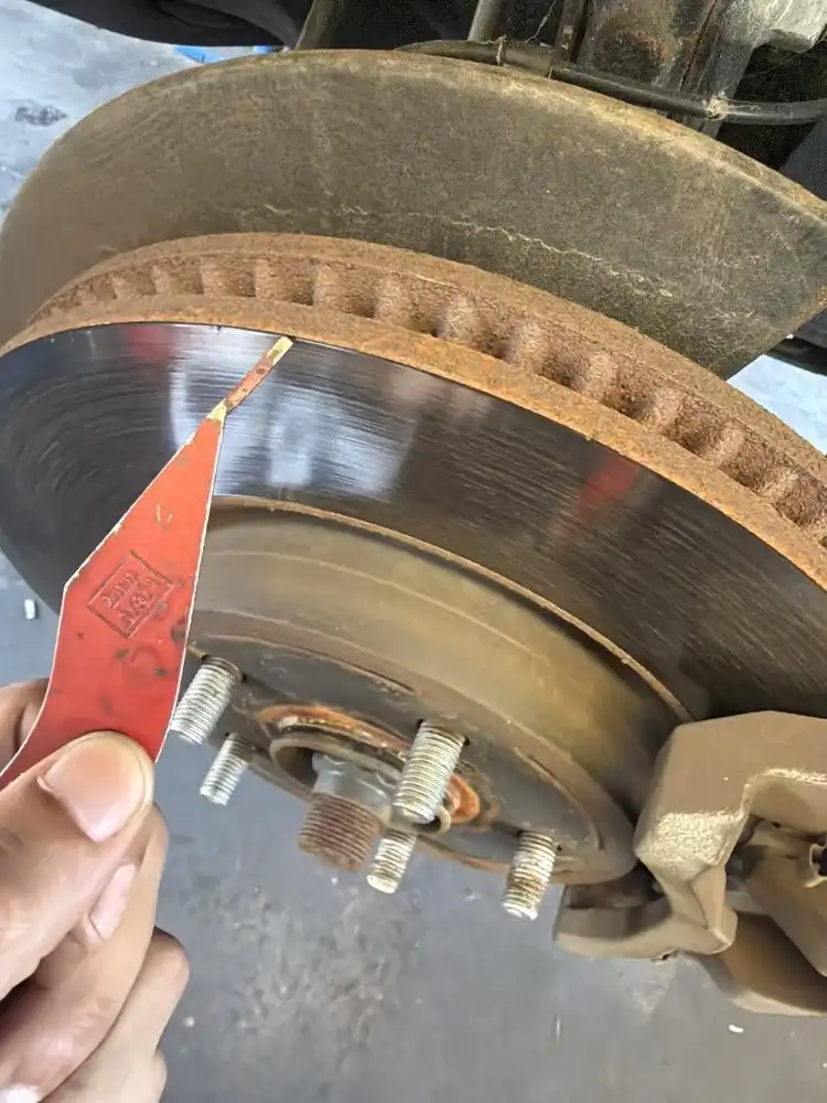Front brake rotor inspection with pad gauge — measuring brake pad friction material at Beacon Auto Care San Mateo